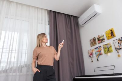 young woman switching on air conditioner while sit utc x